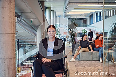 In a modern office, a young businesswoman in a wheelchair is surrounded by her supportive colleagues, embodying the Stock Photo