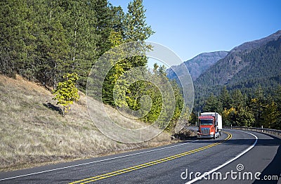 Modern orange big rig semi truck with semi trailer moving on the Stock Photo