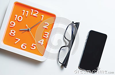 Modern Orange Clock Glasses and smart phone Stock Photo