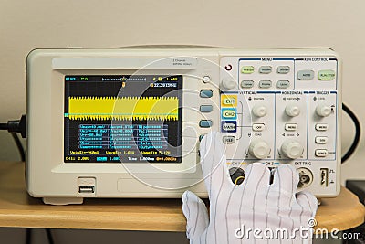 Modern oscilloscope, man`s hand adjusting wave signals, closeup Stock Photo