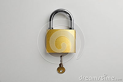 Modern padlock with key on light background, flat lay Stock Photo