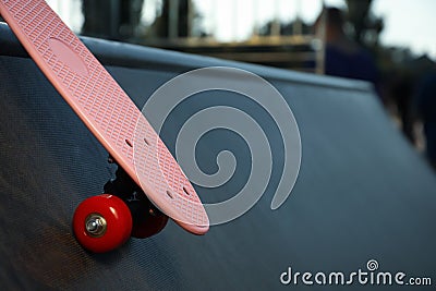 Modern pink skateboard with red wheels on ramp outdoors, closeup. Space for text Stock Photo