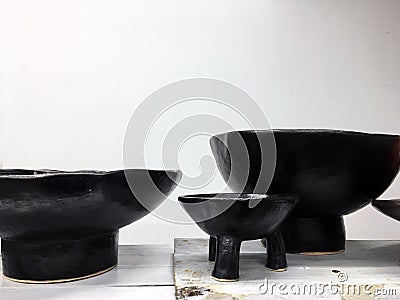 Modern pottery on wooden shelf. Decorative ceramic plate. Handmade dark pottery. Ceramic clay empty handmade bowl and cup on dark Stock Photo