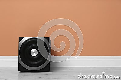 Modern powerful subwoofer on floor near orange wall, space for text. Audio speaker system Stock Photo