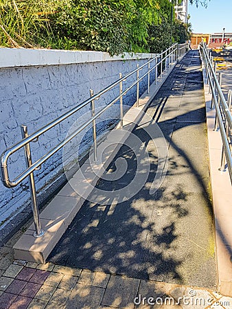 Modern ramp with shiny metal railings outdoors, wheelchair accessible, close-up, vertical Stock Photo