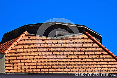 Red clay roof tiles on sloped house roof. galvanized metal flashing. metal snow breakers. Stock Photo