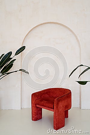 Modern red velour armchair against beige wall Stock Photo