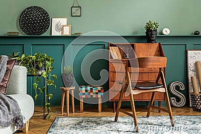 Modern and retro composition of home office interior with wooden cabinet, chair, plants, decoration. Stock Photo