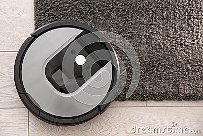 Modern robotic vacuum cleaner on dark carpet. Space for text Stock Photo