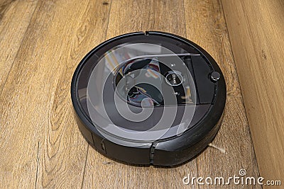 A modern robotic vacuum cleaner running on vinyl panels, an autonomous cleaning robot. Stock Photo