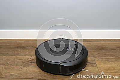 A modern robotic vacuum cleaner running on vinyl panels, an autonomous cleaning robot. Stock Photo