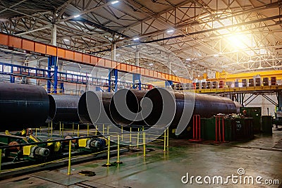 Modern seam pipe factory production line. New manufactured pipes on roller conveyor Stock Photo