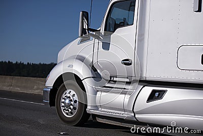 Modern silver big rig semi truck driving by interstate highway Stock Photo