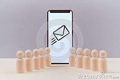 Modern smartphone with envelope sign on screen. Wooden miniatures of people, copy space. Messaging, chatting, email app Stock Photo