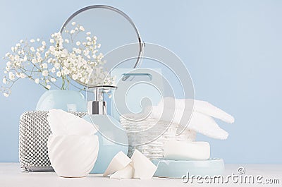 Modern soft light interior for bathroom - pastel blue ceramic bowls, flowers, mirror, silver cosmetic accessories on white wood. Stock Photo