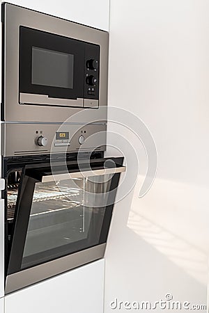 Modern steel microwave and opened oven in kitchen Stock Photo