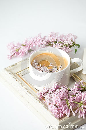 Modern still life with lilac flowers, frame and cup of coffee, on white wbackground, copy space. Holiday or wedding background. Stock Photo