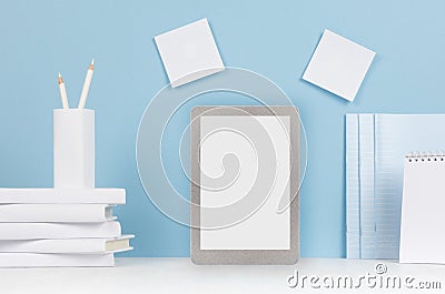 Modern style workplace - white stationery, blank tablet computer on soft blue background and light desk. Stock Photo