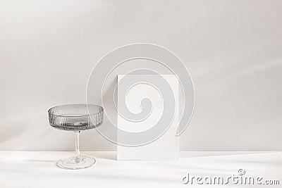 Modern summer still life scene. Grey chanpagne textured glass with drink in sunlight with long shadows. Blank greeting Stock Photo