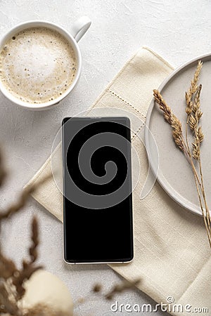 Modern tabletop with with smartphone mockup, cup of coffee, dried plants and notebook on textured white background. Flat lay, Stock Photo