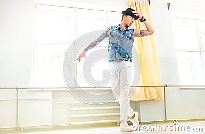 Modern tattooed art dancer teenager dressed in jeans vest, white pants and black hat dancing and mirror posing portrait Stock Photo