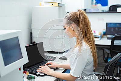 Modern technology in science. Scientist entering data of analysis or research results to laptop at laboratory. Stock Photo