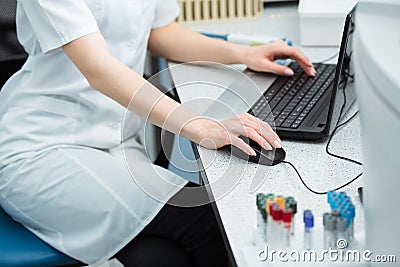 Modern technology in science. Scientist entering data of analysis or research results to laptop at laboratory. Stock Photo