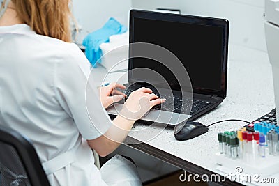 Modern technology in science. Scientist entering data of analysis or research results to laptop at laboratory. Stock Photo