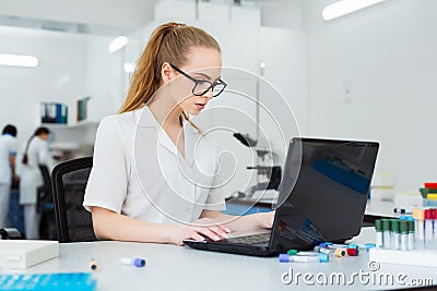 Modern technology in science. Scientist entering data of analysis results to laptop at laboratory Stock Photo