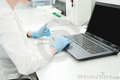 Modern technology in science. Scientist entering data of analysis results to laptop at laboratory Stock Photo