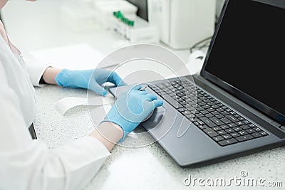 Modern technology in science. Scientist entering data of analysis results to laptop at laboratory Stock Photo