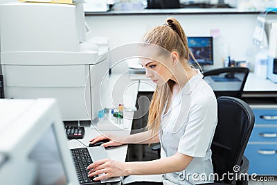 Modern technology in science. Scientist entering data of analysis results to laptop at laboratory. Stock Photo