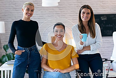 Modern three entrepreneur women looking at camera while staying in the office Stock Photo