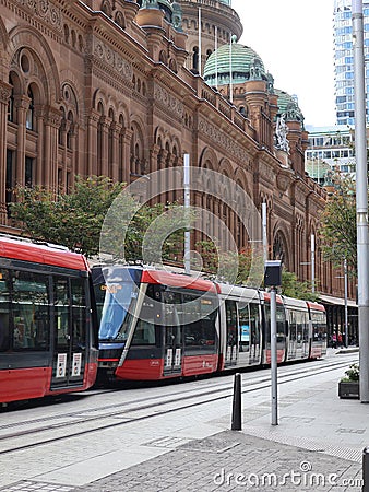 A Modern Tram passing by a Classic and Mid-Century Building Editorial Stock Photo