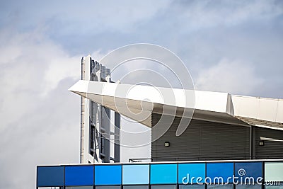 Modern urban architecture blue and aqua building angled roofline with chrome stainless steel chimneys reaching to the cloudy sky Stock Photo