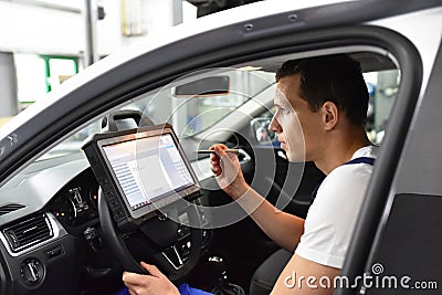 Modern vehicle diagnosis with computer in a garage - mechanic in Stock Photo