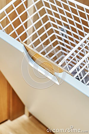 Modern wardrobe with opened metal mesh laundry basket. Wooden wardrobe with light gray cabinet doors. Close-up Stock Photo
