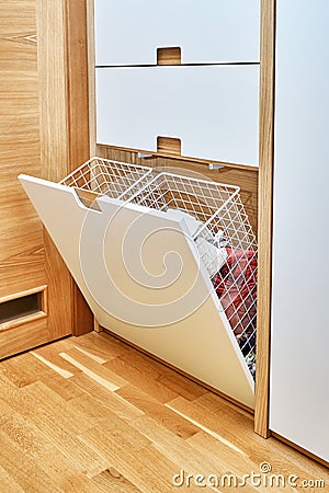 Modern wardrobe with opened metal mesh laundry basket. Wooden wardrobe with light gray cabinet doors Stock Photo