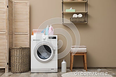 Modern washing machine near color wall in laundry room interior Stock Photo
