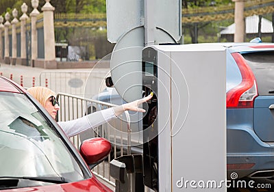 Young driver woman pressing a button on parking machine. Stock Photo