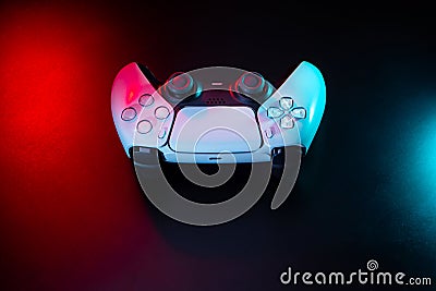 Modern white gamepad illuminated in red and blue. Game controller for video games and e-sports on a dark back Stock Photo