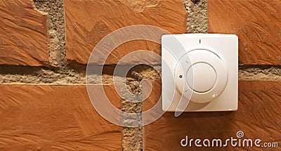 Modern white room and floor heating controller on a brick wall, close-up. Adjustment of the comfortable temperature in the room. Stock Photo