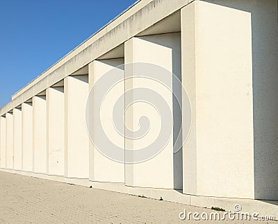Modern white stone colonnade with tiled pavement in front. Stock Photo