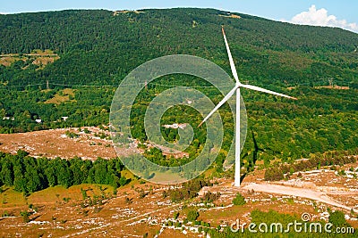 Wind driven generator operates against big forestry mountain Stock Photo