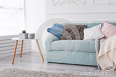 Modern wooden coffee table and cozy sofa with pillows. Living room interior and simple modern home decor concept. Stock Photo