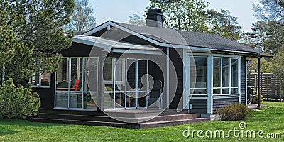 Modern wooden house with green grass, trees and sky with clouds at the background Stock Photo