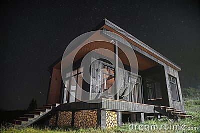 Modern wooden tiny cabin at night with sky full of stars Stock Photo