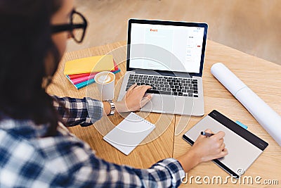 Modern work image young brunette woman in black glasses from back working with laptop on table. Creativity, graphic Editorial Stock Photo