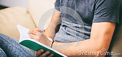 Left handed man writing, sitting on a sofa Stock Photo