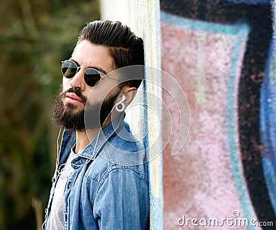 Modern young man with beard listening to music with earphones Stock Photo
